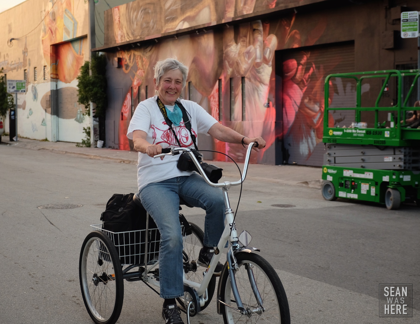 Martha Cooper riding her 3 wheeler documenting Wynwood. Background is Case Maclaim with a mural in progress. Wynwood Miami